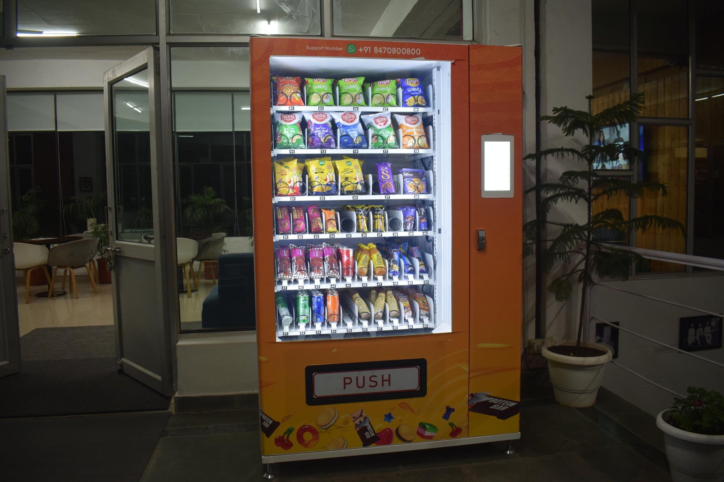 An orange Wendor vending machine lit up at a university building entrance at night