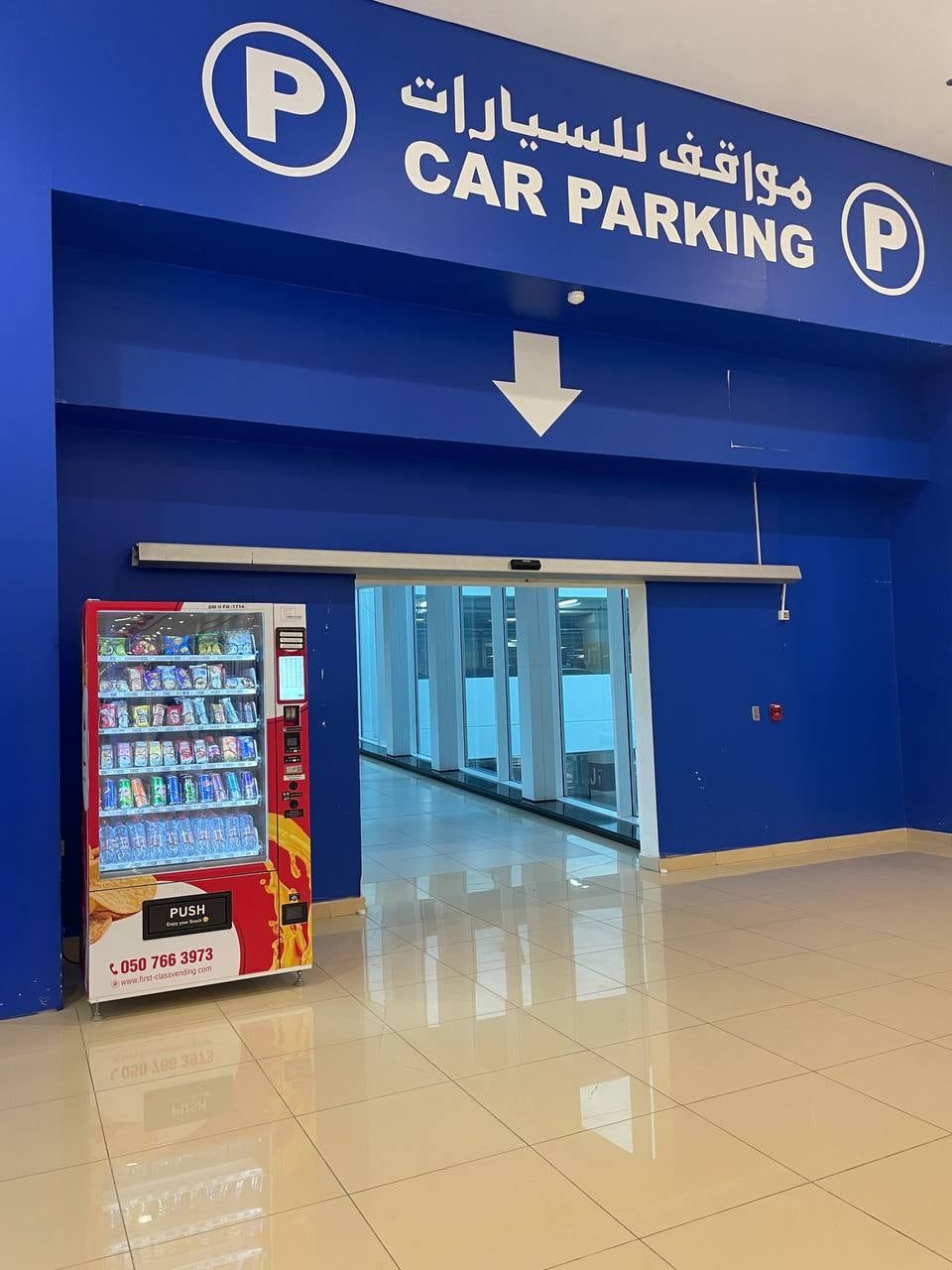 A red Wendor vending machine beside a mall car-park entrance in Dubai, with bilingual parking signage
