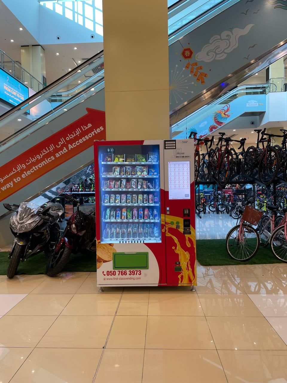A red Wendor machine by an escalator in a Dubai mall