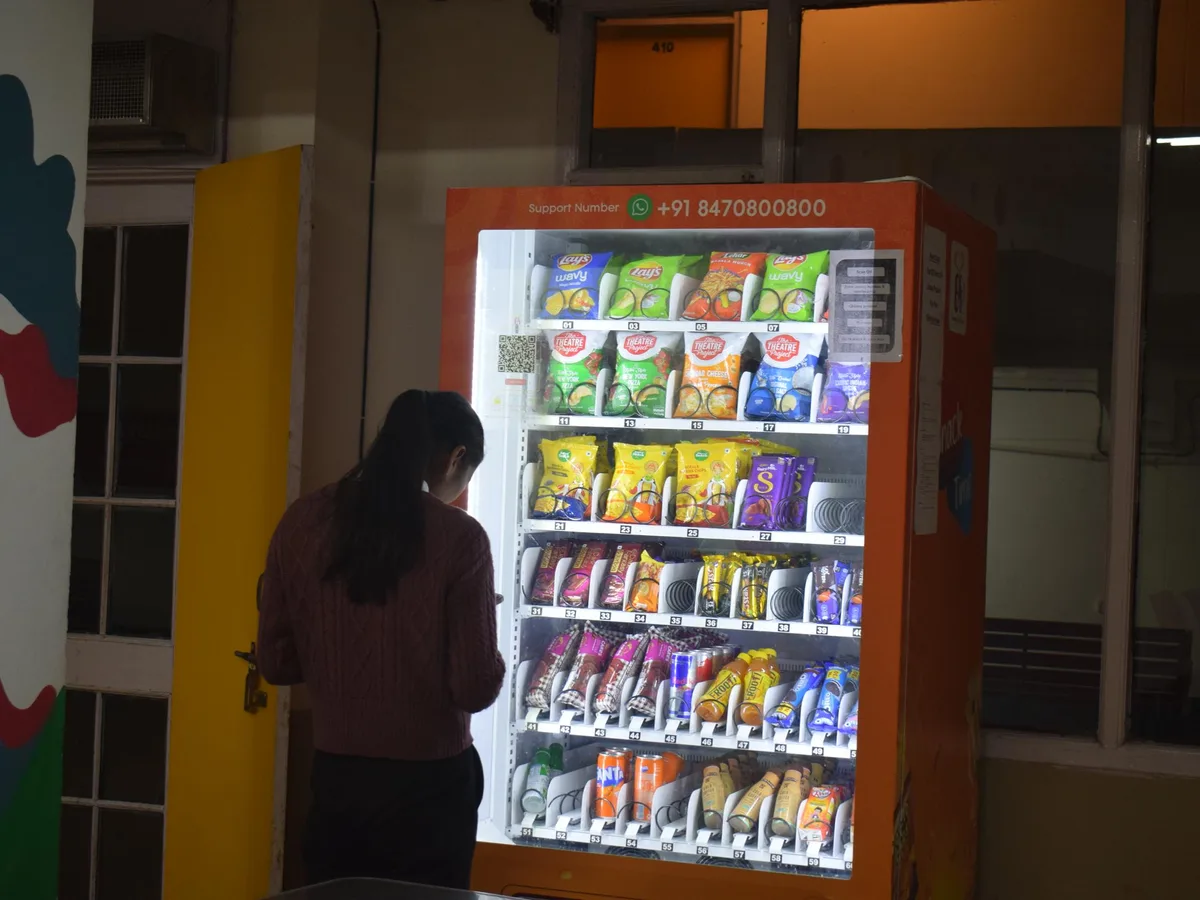 Operator arranging vending shelves while checking sales trends on a tablet