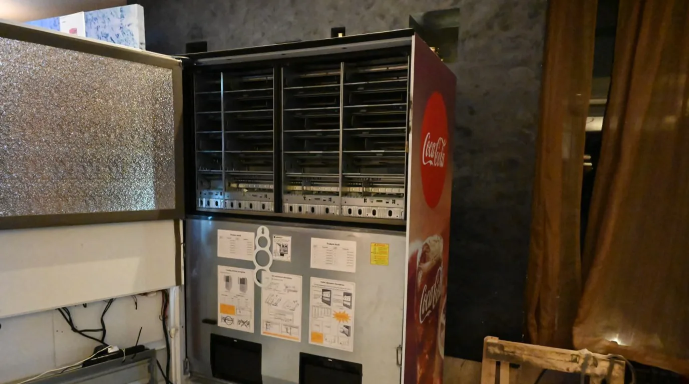 Operator counting precise par-level stock into a bin beside a vending machine