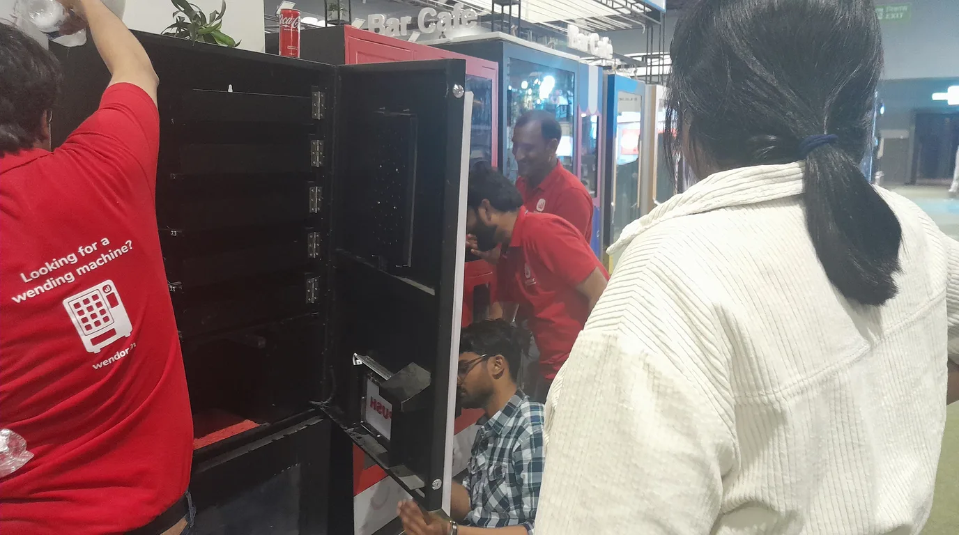 A single modern vending machine in a busy location with passing foot traffic